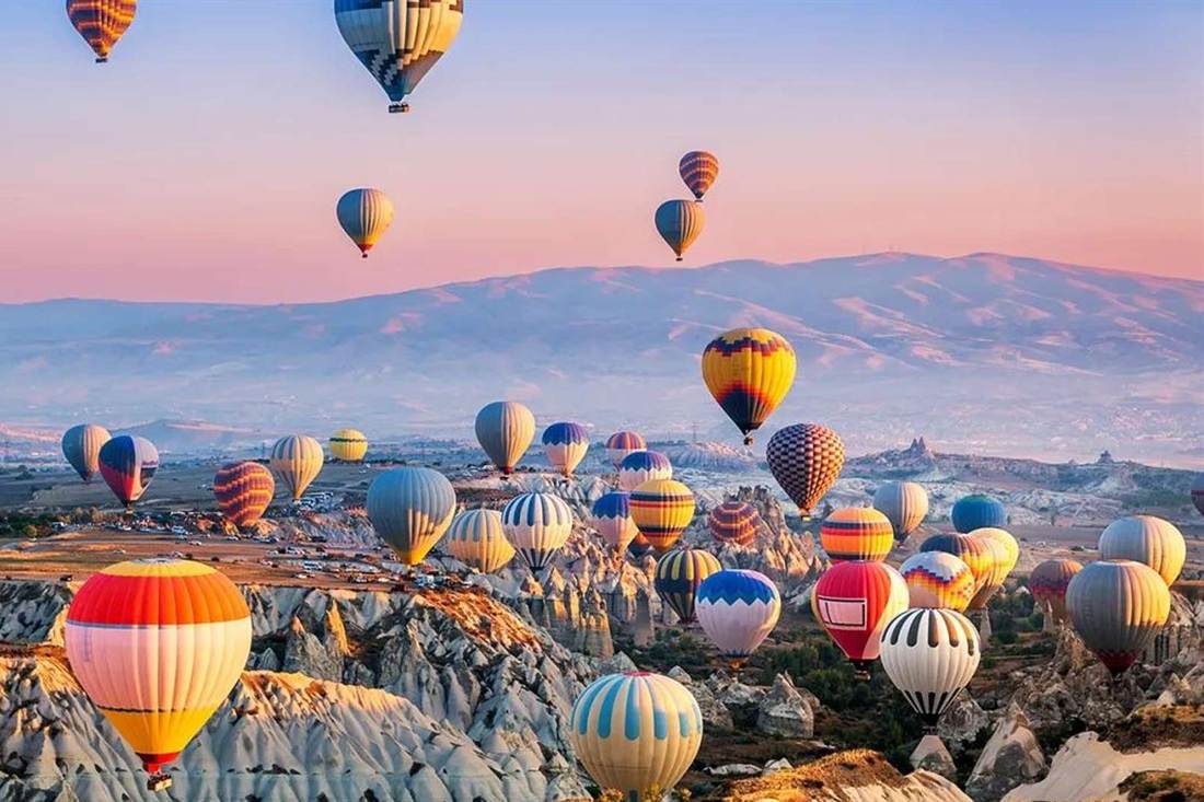 Hot air balloons drifting over the rocky valleys of Cappadocia.